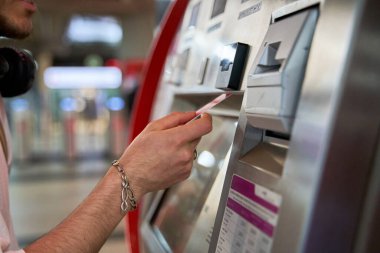 Yakın çekim bir adamı tren istasyonunda yakalar, bilet almak için bir kart ya da para koyar, yolculuğuna hazırlanır ve yolculuğun heyecanını kucaklar..