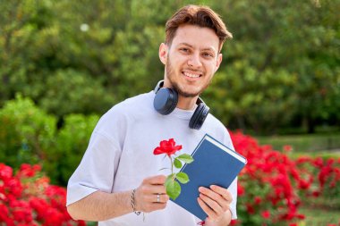 Parktaki genç bir Latin adamın portresi. Elinde bir kitap ve bir gül var.