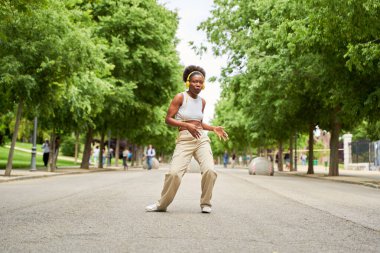 Afrikalı bir Amerikalı kadın kulaklıklarıyla müzik dinlerken günlük rutininde ritmik bir kaçışın tadını çıkarıyor..