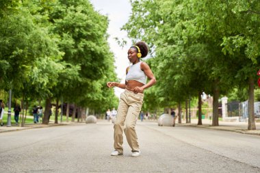 Afrikalı bir Amerikalı kadın kulaklıklarıyla müzik dinlerken günlük rutininde ritmik bir kaçışın tadını çıkarıyor..