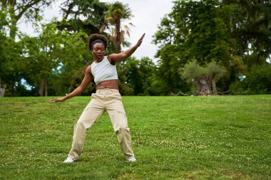 Afrikalı bir kadın hip hop dansı yapıyor. Açık havada dans ediyor. Enerjisini ve yeteneğini canlı ve canlı bir ortamda sergiliyor..