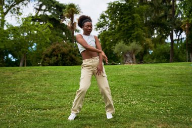 Afrikalı bir kadın hip hop dansı yapıyor. Açık havada dans ediyor. Enerjisini ve yeteneğini canlı ve canlı bir ortamda sergiliyor..