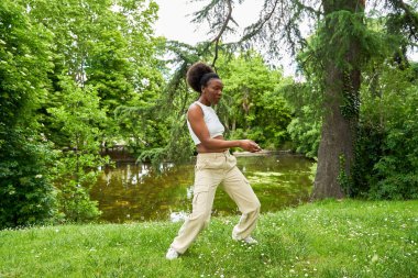 Afrikalı bir kadın hip hop dansı yapıyor. Açık havada dans ediyor. Enerjisini ve yeteneğini canlı ve canlı bir ortamda sergiliyor..