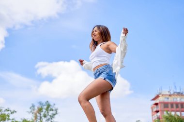 Latin bir kadın parkta dans ederken doğal ve açık havada dans etme isteğini ve zarafetini sergiliyor..