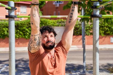 Bir adam açık hava ortamında fiziksel kondisyon, azim ve dayanıklılık göstererek, açık hava jimnastik parkında yoğun bir antrenman yapar..