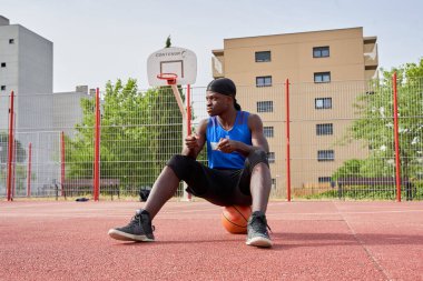 Siyah adam basketbol oynamak için geriniyor.