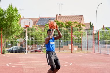 Bir adam basketbol oynar ve topa atlamak için zıplar..