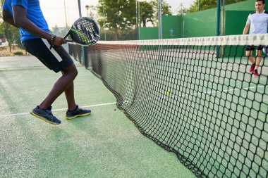 Mavi gömlekli bir adam raketle tenis oynuyor..