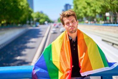 Köprüde gökkuşağı bayrağı taşıyan biri. Bayrak, LGBTQ toplumunun bir sembolüdür.