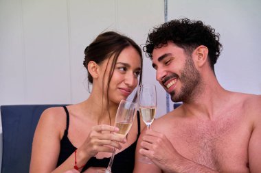Şampanyayla kadeh kaldıran ve romantik bir anı paylaşan çift
