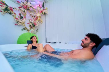 Güzel çiçeklerle dolu bir jakuzide dinlenen çift.