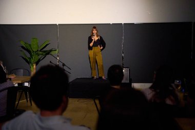 Alternatif bir tiyatroda seyircilerle birlikte sahnede bir monolog sunan kadın sanatçı.