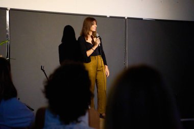 Alternatif bir tiyatroda seyircilerle birlikte sahnede bir monolog sunan kadın sanatçı.