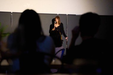 Alternatif bir tiyatroda seyircilerle birlikte sahnede bir monolog sunan kadın sanatçı.