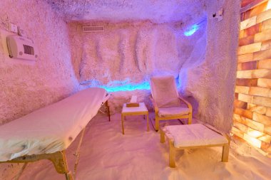 Masaj masası ve rahatlatıcı bir atmosferi olan tuzlu terapi odası.