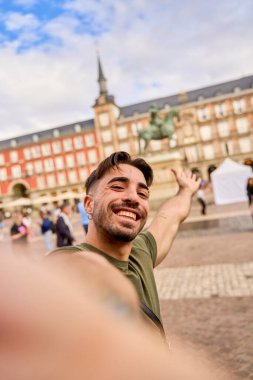 Şehir meydanında tarihi heykelin önünde selfie çeken bir adam.