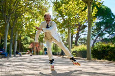 Parkta neşeli bir ifadeyle paten kayan adam.