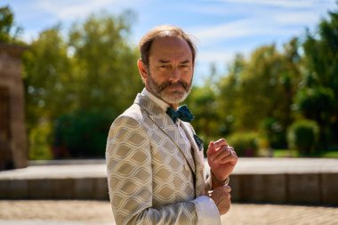 Güneşli bir günde açık havada poz veren kendine güvenen takım elbiseli bir adam.