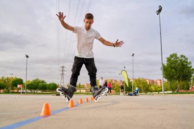 Adam parkta külahları yönetirken patenlerin üzerinde zıplıyor.