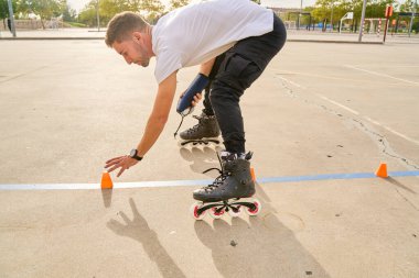 Adam açık hava parkında paten kayarken külahları ayarlıyor.