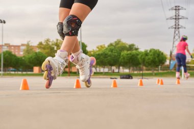 Koruyucu ekipmanlarla paten kayma alıştırması yapan bacakların yakın çekimi.