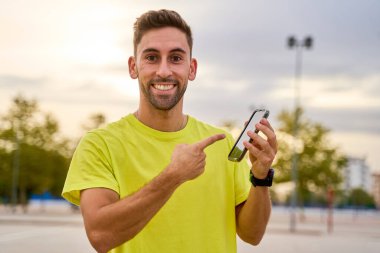 Gülümseyen paten hocası dışarıdaki akıllı telefonu işaret ediyor.