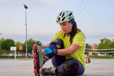 Açık hava sporları alanında paten ayarlayan bir kadın.