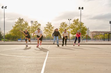 Güneşli bir günde patenci grubu açık havada yarışıyor.