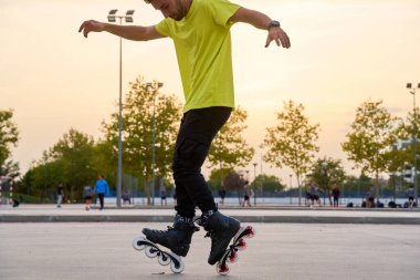 Adam gün batımında parkta paten numaraları yapıyor.