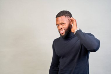 Elini kulağına dayamış, ilginç bir ifadeyle dikkatle dinleyen genç bir işadamının stüdyo portresi.