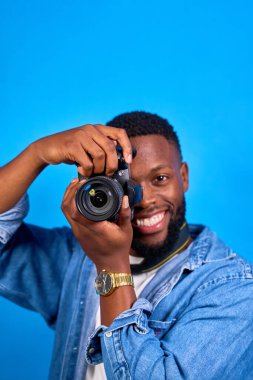 Fotoğrafçı dijital kamerayla fotoğraf çekiyor, gülümsüyor ve işine olan tutkusunu ifade ediyor.