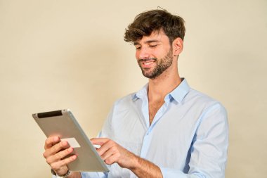 Genç işadamı gülümsüyor ve dijital tablet kullanıyor, mobil teknolojinin ve iş için çevrimiçi bağlantının tadını çıkarıyor