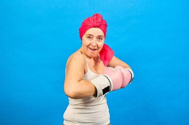 Güçlü bir kadın pembe boks eldiveni ve başörtüsü takıyor, kanserle savaşmaya hazır, cesaret ve umudu temsil ediyor.