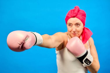 Pembe boks eldiveni giyen kararlı bir kadın, kanserle mücadelesini simgeleyen güçlü bir yumruk atıyor.