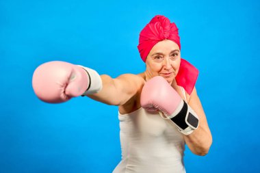 Pembe başlıklı kadın ve beyaz gömlek elinde pembe boks eldivenleri tutuyor.