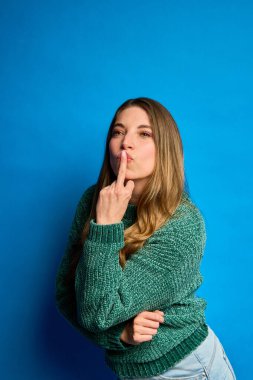 Genç bir kadın, sessiz bir jest yapıyor. Parmağı dudaklarında. Gizliliği ya da sessizliği ifade ediyor.
