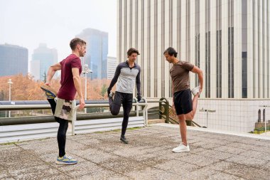 Canlı bir şehir ortamında bacaklarını esneten üç adam, sabahları birlikte canlandırıcı bir açık hava antrenmanına hazırlanıyorlar.