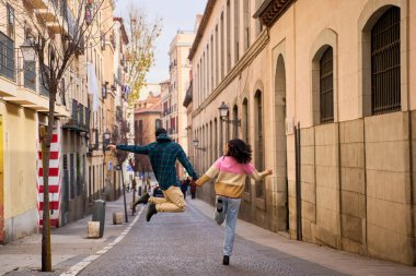 Bir çift el ele tutuşuyor, atlıyor ve şehir sokaklarında koşuyor, birlikte kaygısız bir günün tadını çıkarıyor.