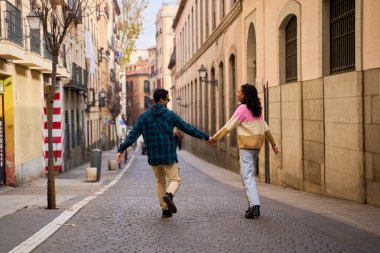 Genç turistler el ele geziyorlar, şehir sokaklarında, neşeyle yeni bir şehri keşfediyorlar ve birlikte uzun süreli anılar yaratıyorlar.