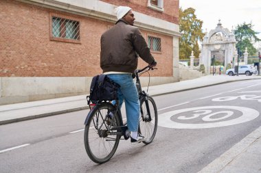 Male courier cycling through a bustling city street, delivering a package on a bicycle equipped with panniers, showcasing urban mobility clipart