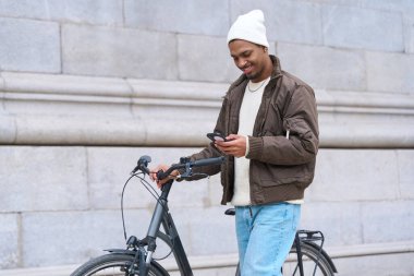 Mutlu adam bisikletiyle yürüyor ve cep telefonu uygulamasını paylaşımda, seyrüsefer ve kentsel hareketlilik için kullanıyor.