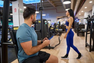 Modern bir spor salonunda spor aletleriyle çevrili, sağlıklı bir yaşam tarzını somutlaştıran iki birey.
