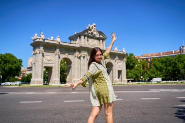 Madrid 'deki Puerta de Alcala anıtının önünde dans eden genç bir kadın, İspanya' daki yaz tatilinin tadını çıkarıyor.