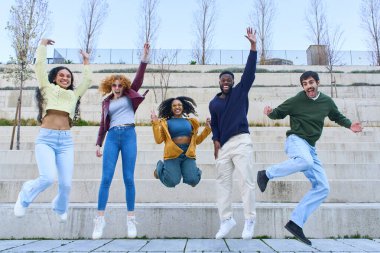 Beş neşeli çoklu etnik öğrenci, zor kazanılmış başarılarını ve başarılarını kutlamak için bir üniversite kampüsünde neşeyle atlıyorlar.