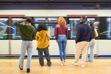 Bir grup genç öğrenci metro istasyonuna varmak için metro istasyonunda bekliyorlar.