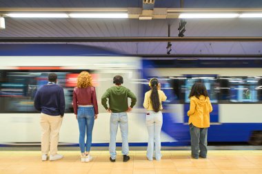 Beş genç öğrenci hareketli bir metro istasyonunda tren bekliyor, kulaklıklarıyla müzik dinliyorlar ve birlikte anlarını paylaşıyorlar.