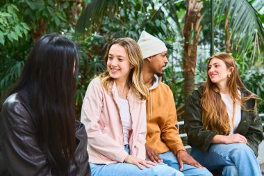 Dört üniversite öğrencisi, bitki dolu bir botanik bahçesinde oturup sohbet etmekten keyif alıyorlar.