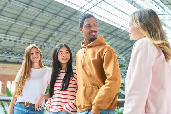 Dört çoklu etnik öğrenci Madrid 'deki tren istasyonunun büyük metal ve cam çatısı altında sohbet ediyorlar.