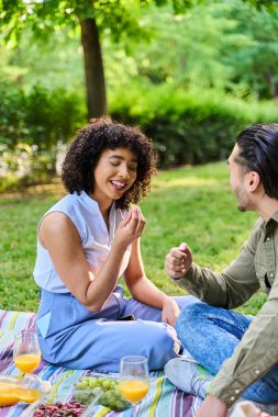 Mutlu çift taze meyve ve portakal suyuyla pikniği paylaşıyor, parkta kaliteli vakit geçiriyorlar.
