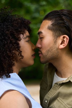 Parkta öpüşen ırklar arası bir çift doğanın güzelliği arasında sevgi ve samimiyetle dolu bir anı kucaklıyor.